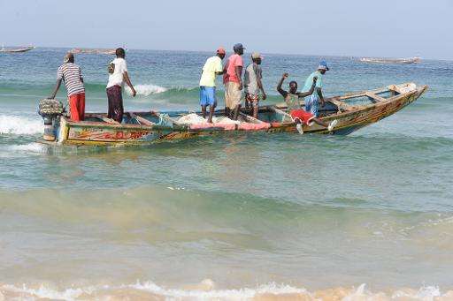 Senegalese fishermen ride a dugout canoe from Kayar beach out to sea, where they are facing competition from Chinese boats fishi
