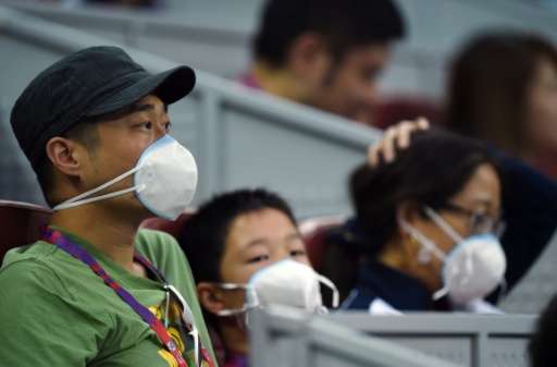 Spectators wear face masks as they watch a  match at the China Open tennis tournament in Beijing on October 5, 2015