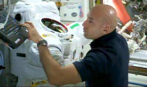 This NASA TV image shows Italian astronaut Luca Parmitano working next to his space suit, which experienced a water-in-helmet le
