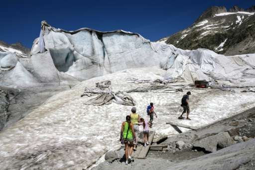 Tourists in July 2015 walk towards an ice cave next to insulating foams wrapping up the Rhone Glacier to prevent it shrinking un