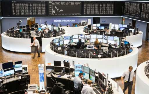 Traders work in front of a board displaying Germany's share index DAX on November 4, 2015 at the stock exchange in Frankfurt am 