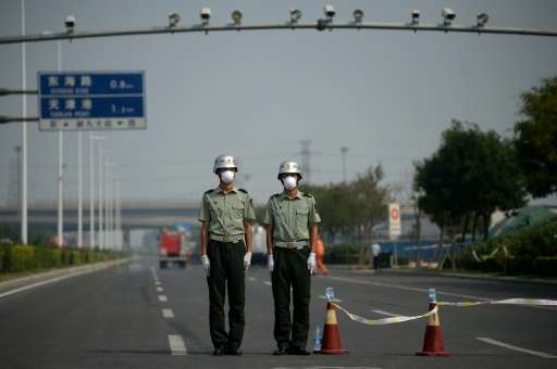 Two soldiers wearing face masks stand at a checkpoint in Tianjin near the site of the explosions at a chemical warehouse that hi