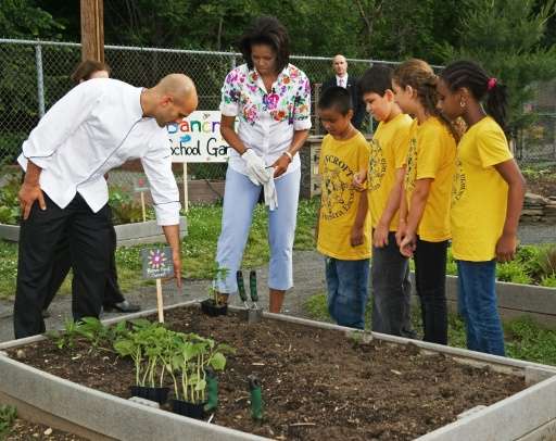 US First Lady Michelle Obama (C) receives some planting advice from White House Assistant Chef Sam Kass (L) while planting veget