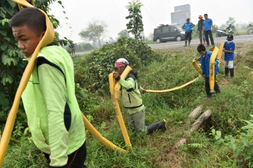 Volunteers carry hoses as they combat forest fires in Kuala Kapuas, Central Kalimantan