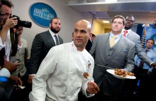 White House Chef Sam Kass (C) serves food to members of the press, prepared with help from Zach Strief (R), a member of the 2010