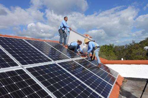 Workers install solar panels on a rooftop on February 20, 2015 at a home in Palmetto Bay, Florida