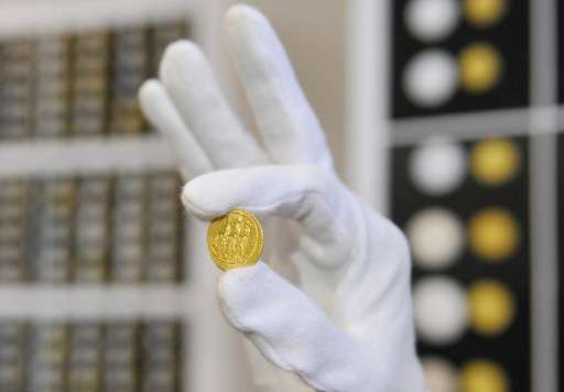 An employee of Romanian National History museum shows a golden coin in Bucharest on November 8, 2013