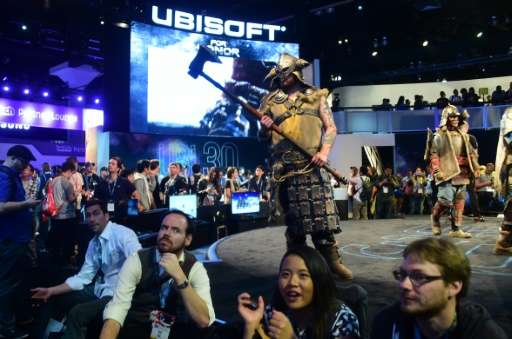 Gaming fans watch the screens as costumed characterizations from the game 'For Honor' by Ubisoft roam the stage during the 2016 
