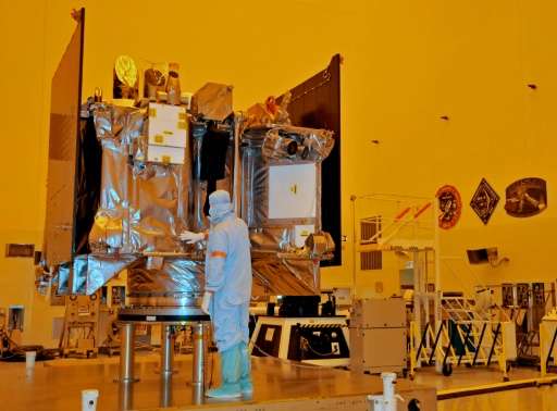 The OSIRIS-REx spacecraft sits on its workstand August 20, 2016 while an engineer checks the protective covering in a servicing 