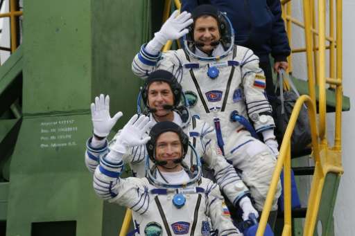 Russian cosmonauts Sergei Ryzhikov (bottom) and Andrei Borisenko (top) and US astronaut Shane Kimbrough wave as they board the S