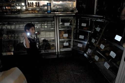 A boy uses a flshlight during a power cut at a bakery in the border state of San Cristobal, 600 km west of Caracas on April 25, 