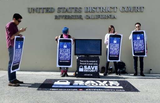 Activists hold placards: &quot;Secure Phones Saves Lives&quot; during a protest in front of the US District Court that was to he