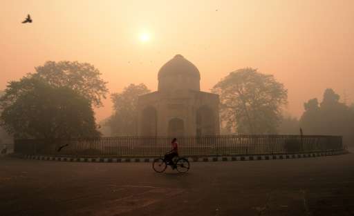 A cyclist rides along a street as smog envelops a monument in New Delhi on October 31, 2016, a day after the Diwali festival