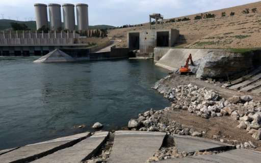 A employee operates an excavator as he works at strengthening the Mosul Dam on the Tigris River