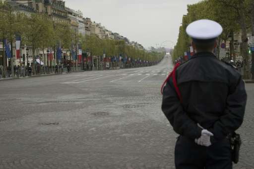 A French policeman stands guard at the top of the empty Champs-Elysees in Paris on April 25, 2016