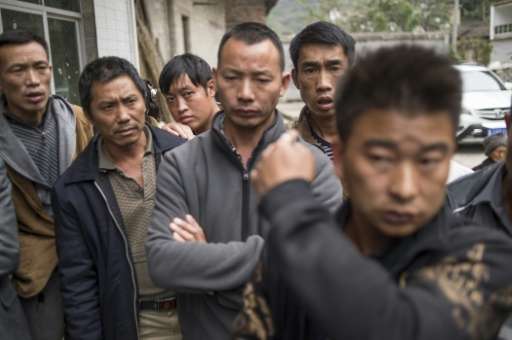 A group of men wait to speak to a journalist in Jinke village, in Pingtang county, after being told to move out of the radio sil