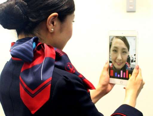 A Japan Airlines flight attendant checking her smile using a Shiseido app