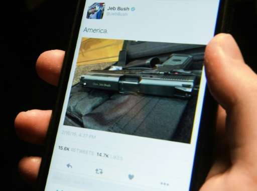 A man looks at a tweet from US Republican presidential candidate Jeb Bush showing a handgun and the caption &quot;America&quot; 