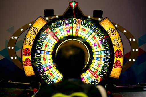 A man tries his luck at a wheel of fortune machine at the Global Gaming Expo Asia held in Macau on May 17, 2016