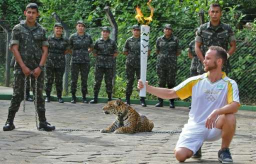 An athlete holds the Olympic Torch by a jaguar, called Juma, during a ceremony in Manaus, Brazil, on June 20, 2016, shortly befo