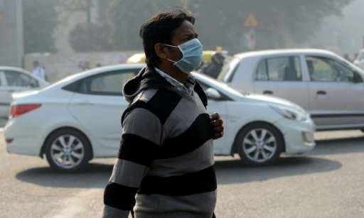 An Indian pedestrian walks with his face covered by a protective mask in New Delhi on December 31, 2015, the day before an exper