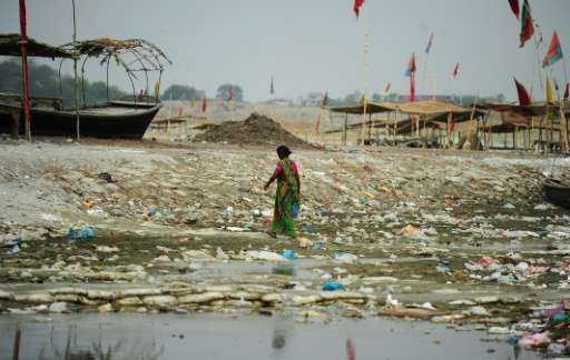 An Indian woman walks amogst plastic bags and garbage strewn on the banks of the River Ganges at Sangam, the confluence of the G