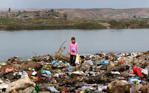 An Iraqi girl stands amid garbage on the banks of the Tigris River in the village of Wana, some 10 kms south of the Mosul Dam