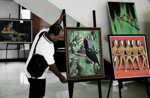 ‌A painter arranges a painting of a rare hornbill species during an exhibition in Pontianak, West Kalimantan province