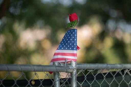A rose and flag stand atop a fence surrounding the scene of the massacre in San Bernardino, California, December 21, 2015