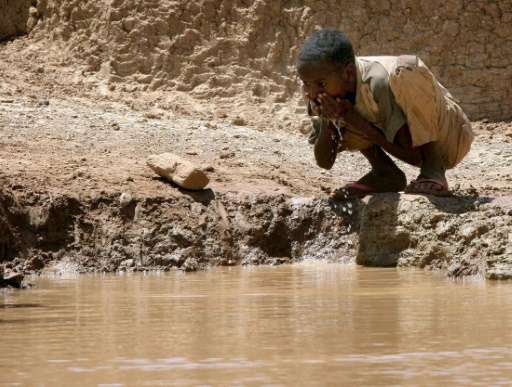 A Somalian boy drinks water at a man-made dam in Bur Dhuxunle village during a drought