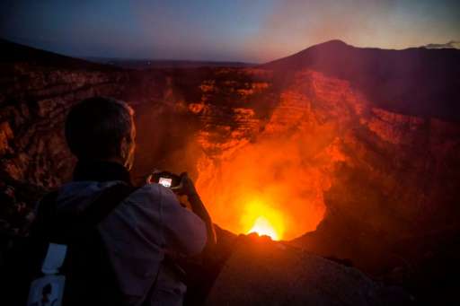 A tourist takes pictures of a lava lake inside the crater of the Masaya Volcano in Nicaragua