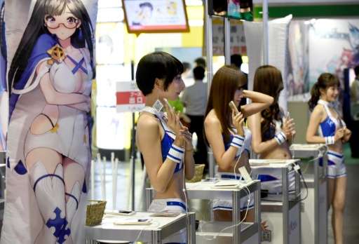 Attendants hold smartphones to introduce games at the Tokyo Game Show 2016 in Chiba, a suburb of Tokyo, on September 15, 2016