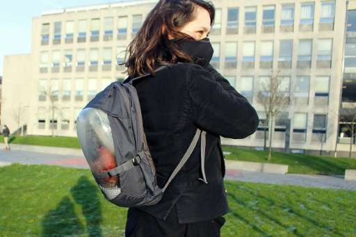 A woman wears &quot;The Plant Bag&quot;, a backpack fitted with a breathing mask connected to the pack which contains a plant on