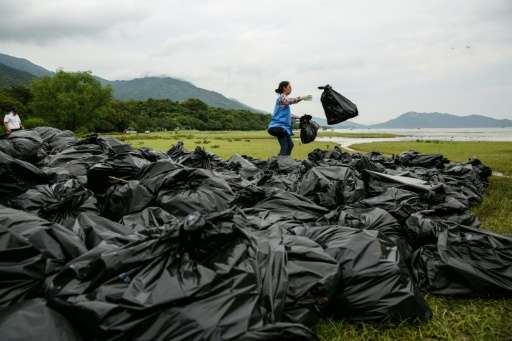 A worker sorts through bags of refuse washed ashore at the top of a beach in Hong Kong on July 10, 2016