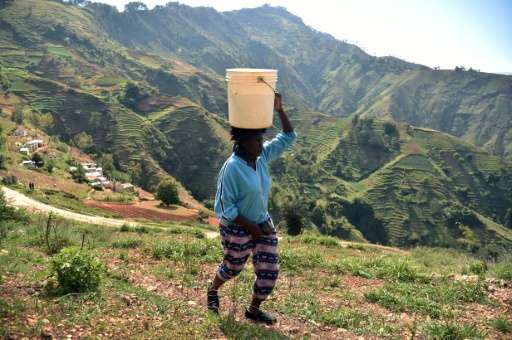 Cathy walks home with a bucket of water on her head in Godet, in the commune of Kenskoff, near the Haitian capital, Port-au-Prin