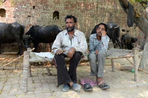 Dharam Veer (L) sits with his disabled son Vineet on a charpoy in the village of Gangnauli, in India's northern state of Uttar P
