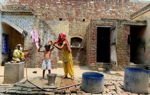 Divya Rathi washes her daughter with contaminated water near their house in the village of Gangnauli, in India's northern state 