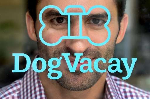 DogVacay co-founder and CEO Aaron Hirschorn poses behind the company's logo on the entrance to company offices in Santa Monica, 