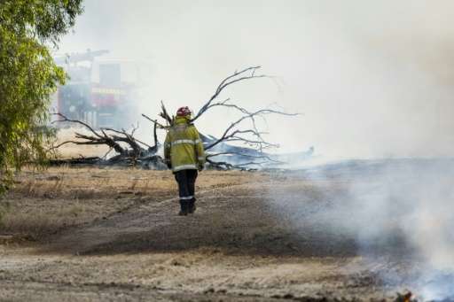 Fireman inspect the damage near Waroona, 70 miles south of Perth, after a huge bushfire which has razed about 71,000 hectares in