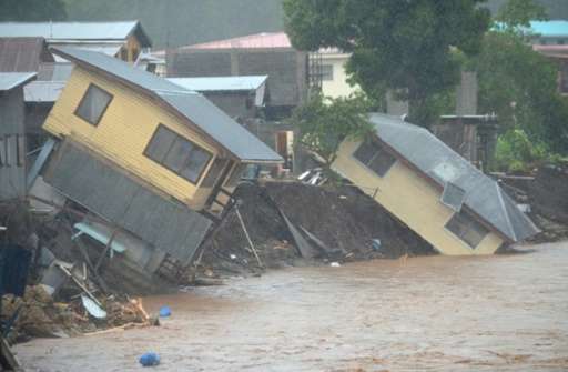 Flood waters run past damaged homes in the Solomon Islands' capital Honiara on April 4, 2014