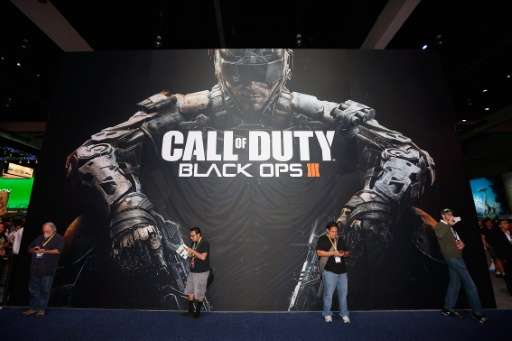 Game enthusiasts stand against a 'Call of Duty Black Ops 3' advertisment during the Annual Gaming Industry Conference E3 at the 
