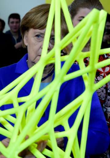 German chancellor Angela Merkel looks at a stool printed by the BigRep One 3D printer during her visit to the Digital Business f