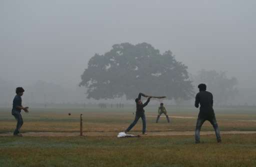 Indian teenagers play cricket in a park as heavy smog covers New Delhi, on November 7, 2016