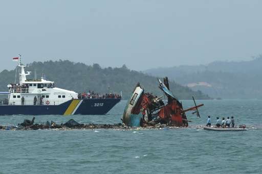 Indonesian navy crew (right) check one of seven fishing boats destroyed in Batam, Kepulauan Riau province on February 22, 2016