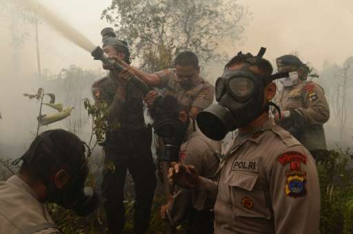Indonesian police and firefighters extinguish a fire on burning peat land in Central Kalimantan province on Borneo island