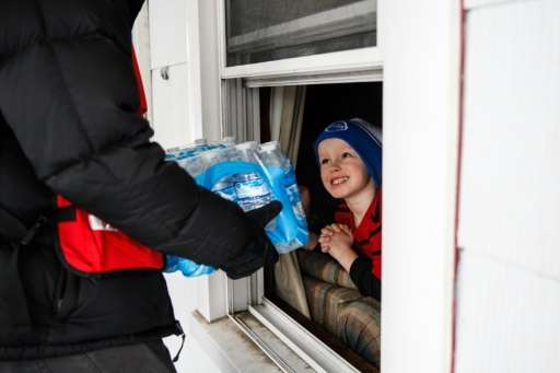 Jake McSigue receives a package of bottled water through the window of his grandma's home on January 21, 2016 in Flint, Michigan