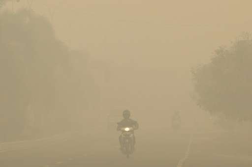 Motorists travel under thick haze in Palembang on Indonesia's Sumatra island