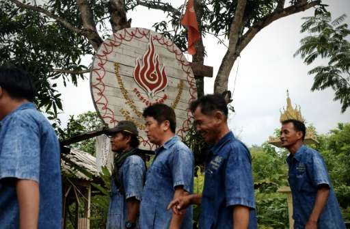 Pa Deng village elders walk past a clean energy sign given to them by Thailand's Ministry of Energy