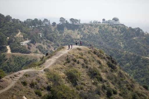 People hike along a ridge overlooking the Griffith Observatory where vegetation is drying out due to lack of rain, in Los Angele