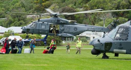 People walking to a helicopter with their suitcases as hundreds of tourists were evacuated from Kaikoura, after an earthquake hi